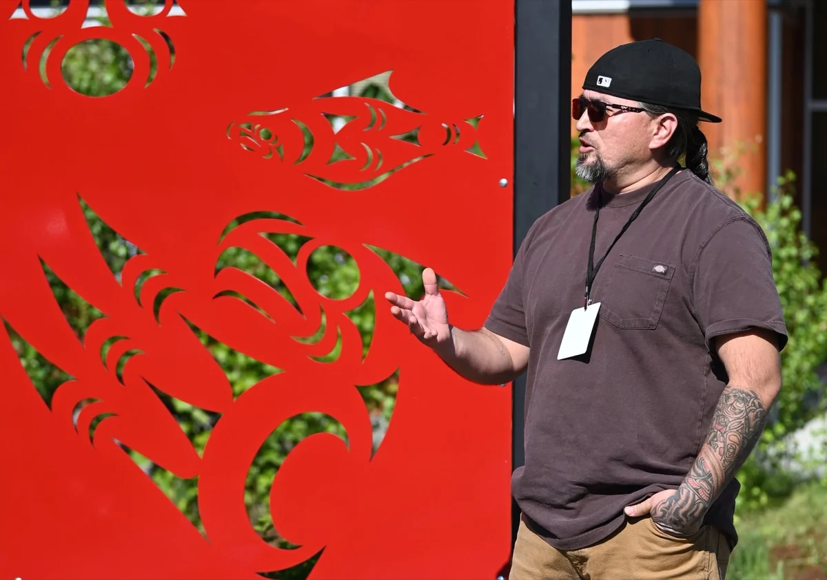 Jason LaClair speaking beside a red public artwork